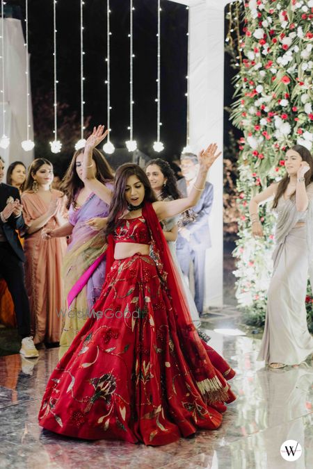 Photo of dancing bride in embroidered red lehenga for her sangeet