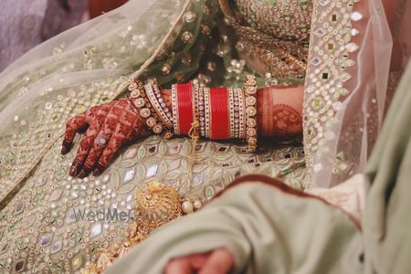 Photo of A shot of red bridal choora with a mint green lehenga