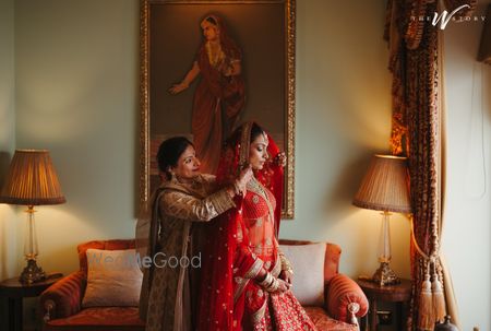 Photo of Lovely capture of the bride of the mom placing the dupatta on the bride's head