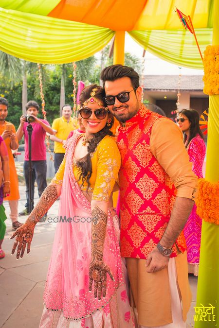 Photo of Bride in yellow and pink lehenga on mehendi