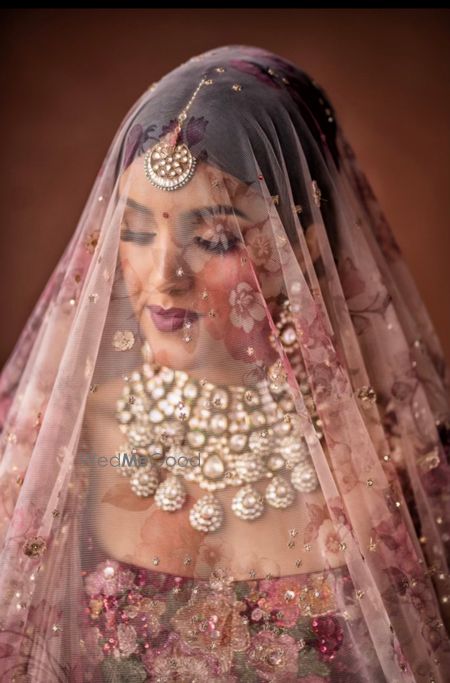 Photo of pretty bridal shot with a printed dupatta as veil