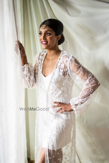 Photo of bride getting ready in lace robe before wedding