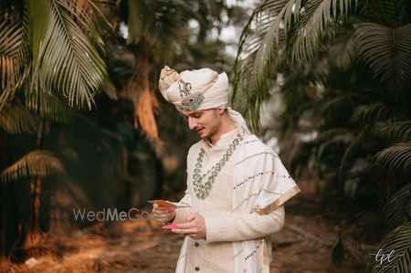 Photo of white groom sherwani with emerald jewellery