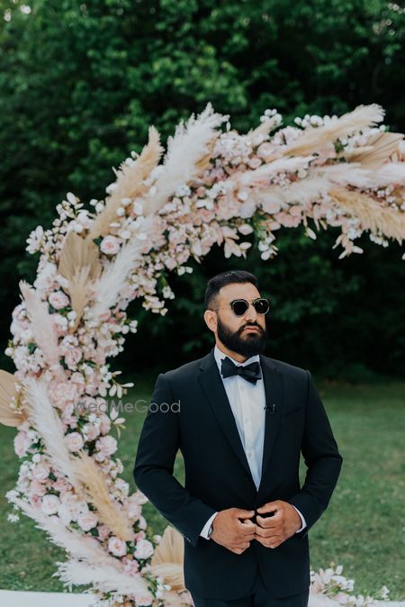 Photo of A groom dressed in a black and white suit