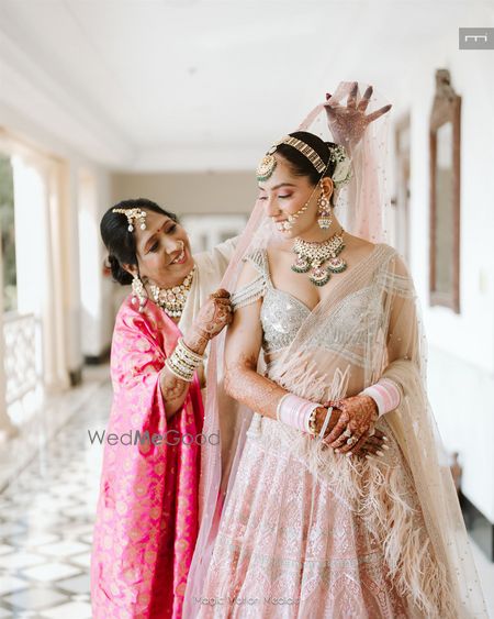 Photo of Mom of the bride placing the dupatta on the bride's head on her wedding day