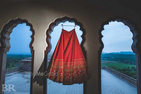 Photo of Bridal red sabysachi lehenga on hanger sunset shot