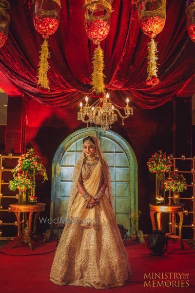 Photo of Bride posing in gold lehenga with red decor