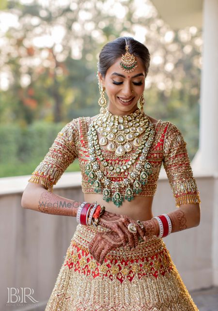 Photo of Heavy red and gold bridal lehenga with layered jewellery