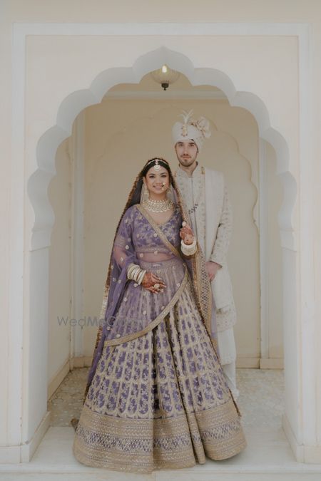 Photo of Lovely couple portrait on wedding day with the bride in a pastel lilac lehenga and groom in a white sherwani