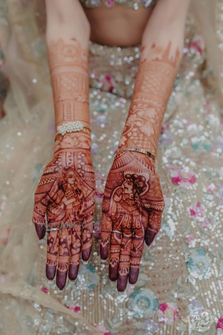 Photo of bridal mehendi design with bride and groom portraits