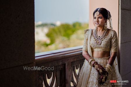 Photo of A bride in an ivory and gold lehenga with stunning jewelry on her wedding day