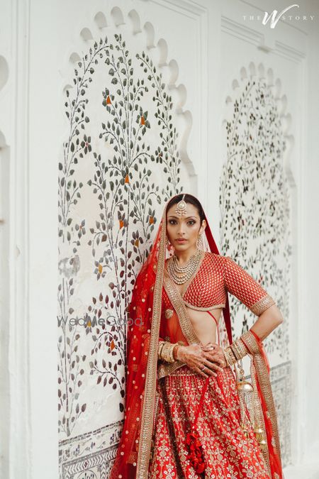 Photo of Classic bridal portrait on the wedding day with the bride in a timeless red lehenga with a plunge neck blouse and diamond jewellery