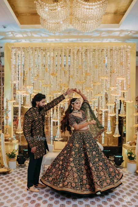 Photo of bride twirling in a dark green manish malhotra lehenga on her mehendi