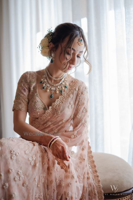 Photo of Gorgeous bride in a peach lace saree with layered emerald and diamond jewellery for the wedding day