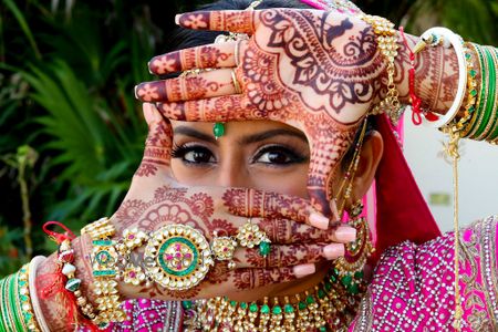 Photo of Bride posing showing off her bridal mehendi and haathphool