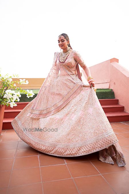 Photo of Bride dressed in pink lehenga posing on her wedding day.