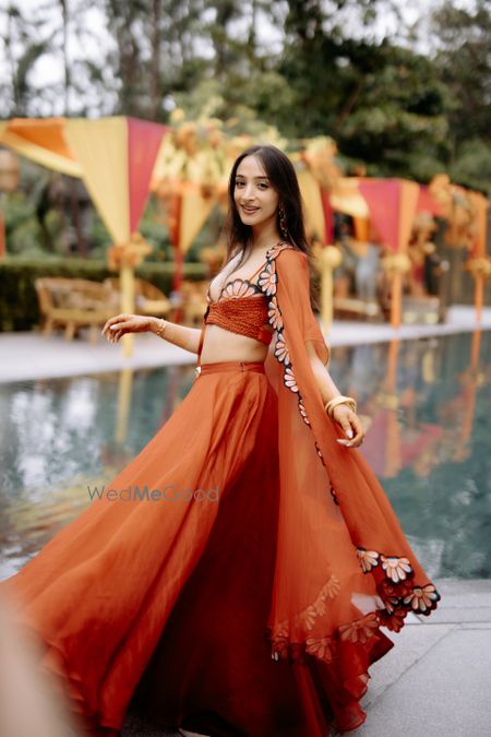 Photo of Fun orange hued lehenga with a jacket style dupatta and scalloped blouse detailing for the mehendi