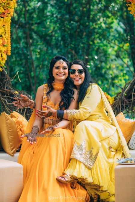 Photo of Bride with sister wearing yellow mehendi outfit