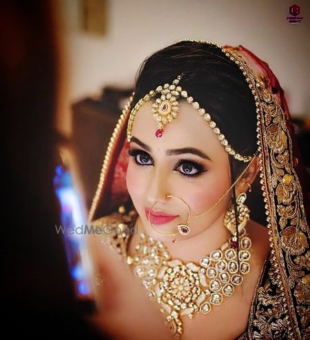 Photo of A bride with peach and gold jewelry poses for the camera.