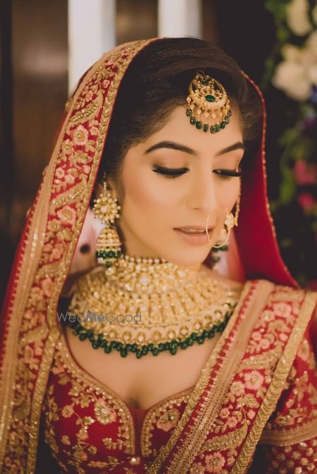 Photo of Bride in red lehenga green jewellery