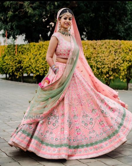 Photo of Bride twirling around in a baby pink lehenga.