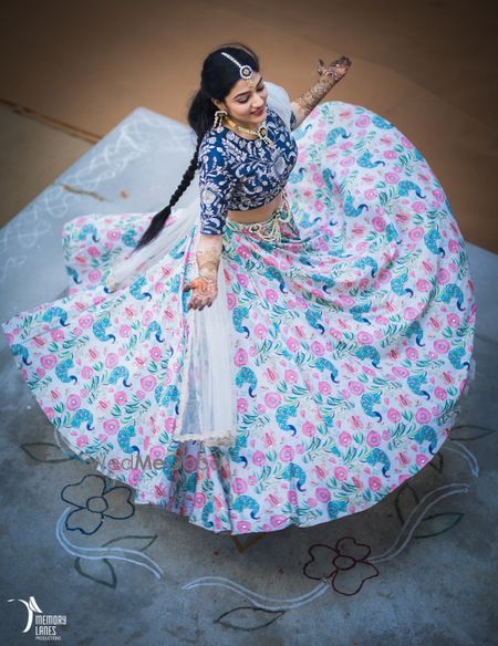 Photo of Bride twirling in offbeat white and blue floral print lehenga