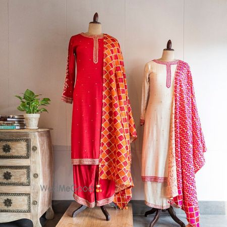 Photo of Bright pink straight suit with orange and pink phulkaari dupatta.
Ivory straight suit with contrasting pink banarasi dupatta.