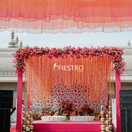 Photo of Haldi decor for seating in pink and orange hues with hanging florals