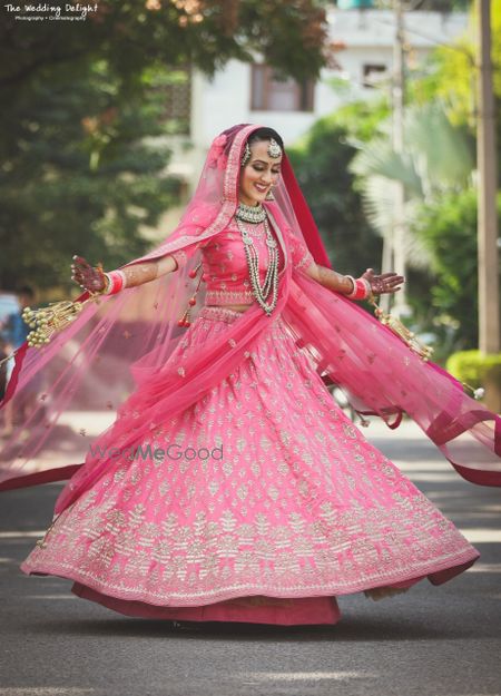 Photo of Sikh bride in bright pink lehenga twirling