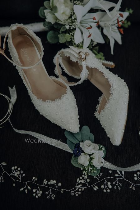 Photo of Bridal Footwear with lacey pattern and pearl embellishments.