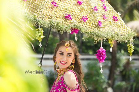 Photo of Bride entering under a floral umbrella on mehendi