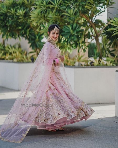 Photo of Twirling shot of a bride dressed in light pink lehenga