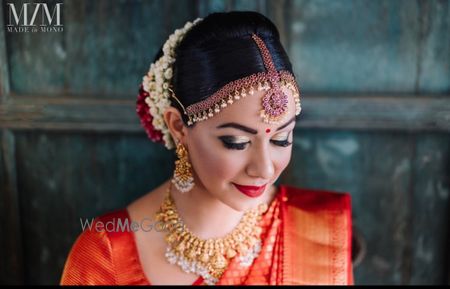 Photo of South Indian bride wearing smokey eyes and red lips.