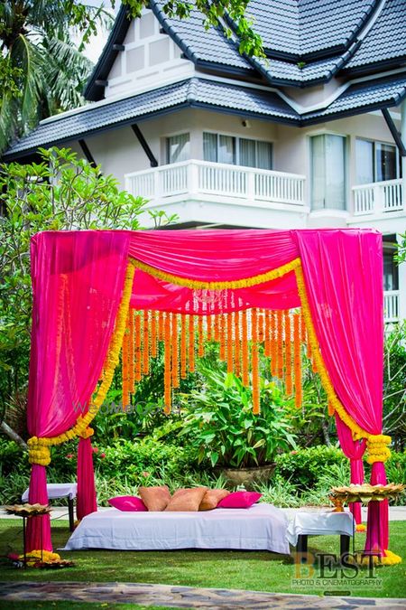 Photo of Bright pink mandap seating with genda phool decor