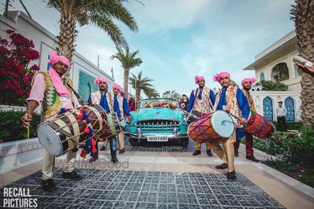 Photo of unique baraat idea with groom entering in bright vintage car