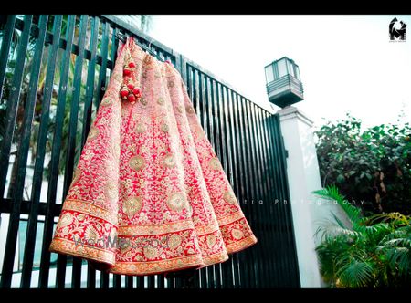 Photo of Bright Pink Lehenga with Red Border on Hanger on Gate