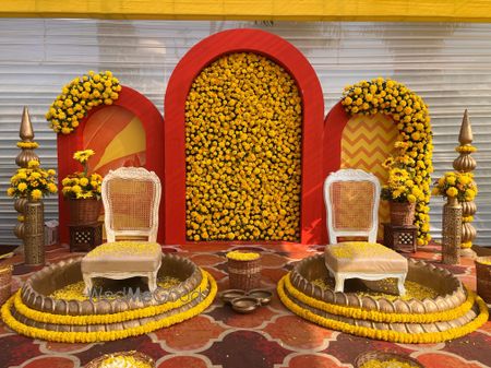 Photo of Stunning gendaphool wall in orange combination for haldi ceremony decor