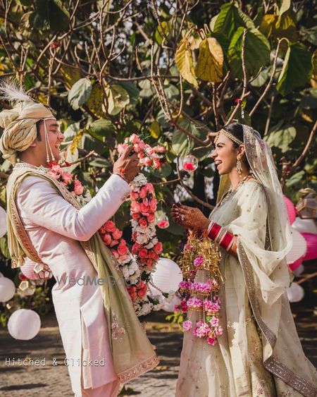 Photo of bright and happy couple shot during jaimala