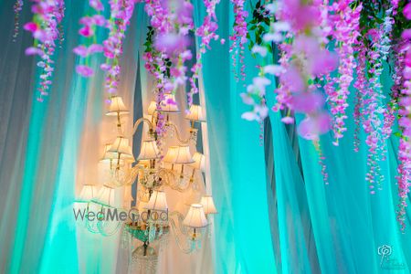 Photo of Hanging chandelier with blue curtains and purple floral