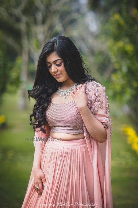 Photo of Bride looking down in lehenga with cape sleeves