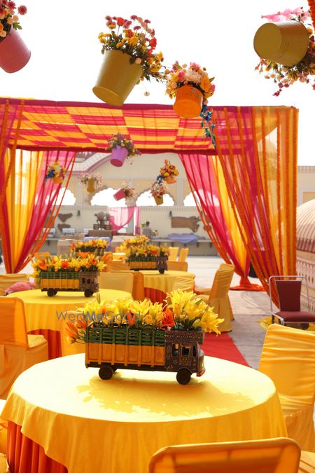 Photo of Hanging flower pots and decorated mini trucks as props for mehendi decor