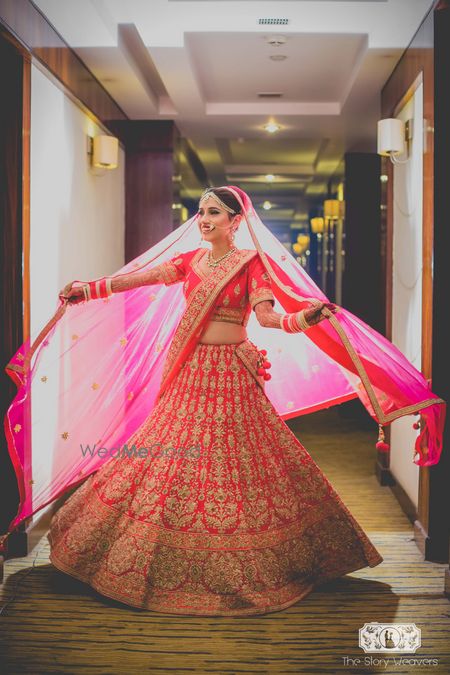 Photo of Bride twirling and posing with dupatta in red lehenga