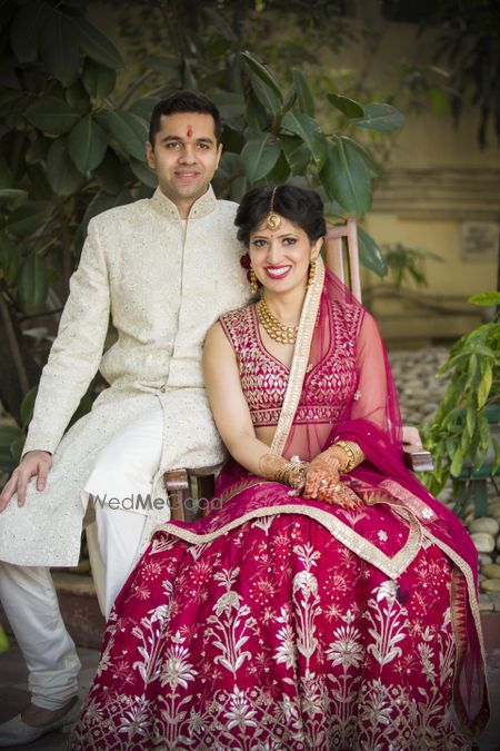 Photo of Coordinated bride and groom with maroon and white outfits