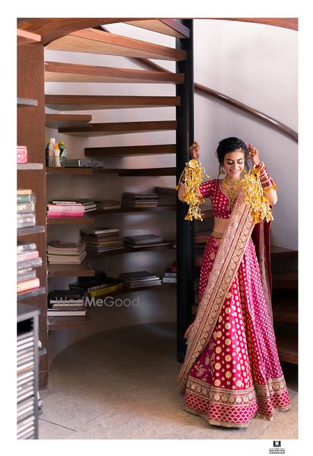 Photo of Bride showing off kaleere in panelled red lehenga