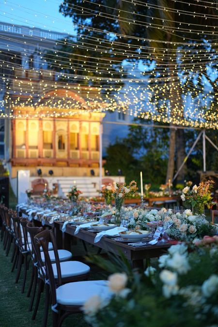 Photo of Gorgeous long table setting with fairylights canopy with floral decor