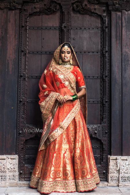 Photo of Red and orange benarasi lehenga with heavy jewellery