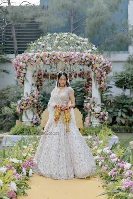 Photo of Bride in a white lehenga against floral mandap