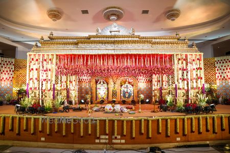 Photo of Grand mandap decor in white and red florals for an indoor wedding