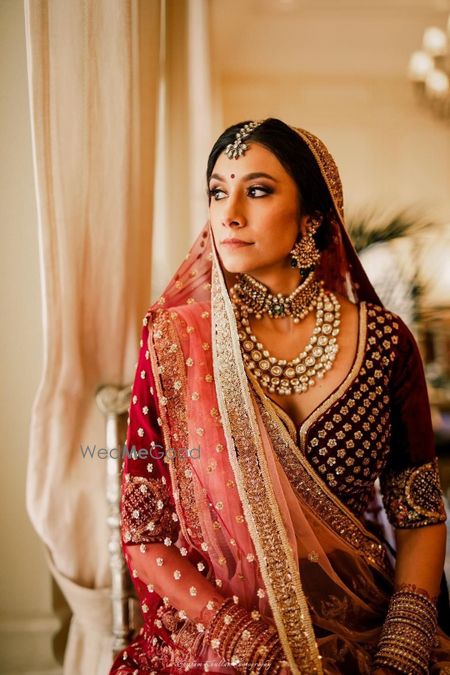 Photo of Bride in layered choker and maroon lehenga