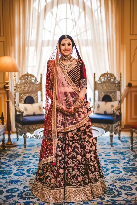 Photo of Bride in maroon floral print velvet lehenga